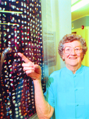 An elderly lady pointing at a false hip amongst fabric containing pills.